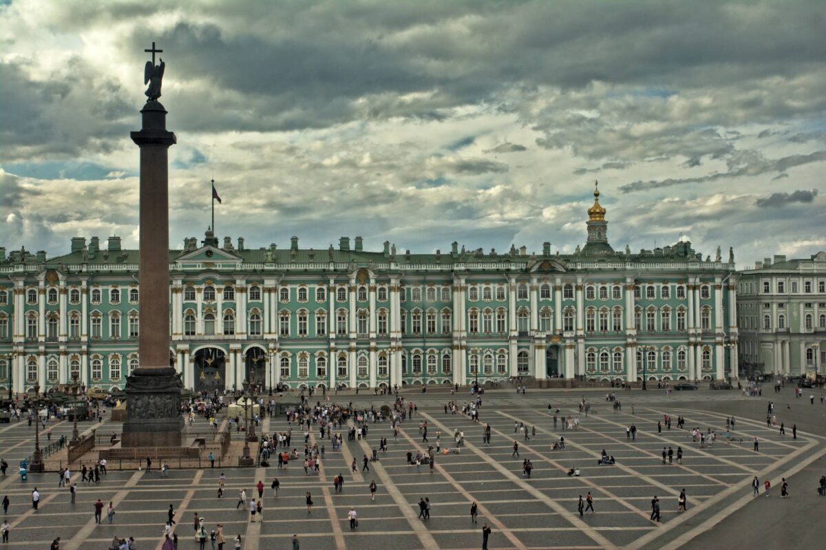 La piazza antistante il Palazzo d'Inverno (uno degli edifici che ospita l'immenso museo di stato dell'Hermitage) a San Pietroburgo. I numerosi turisti sono figure insignificanti all'ombra della poderosa Colonna di Alessandro