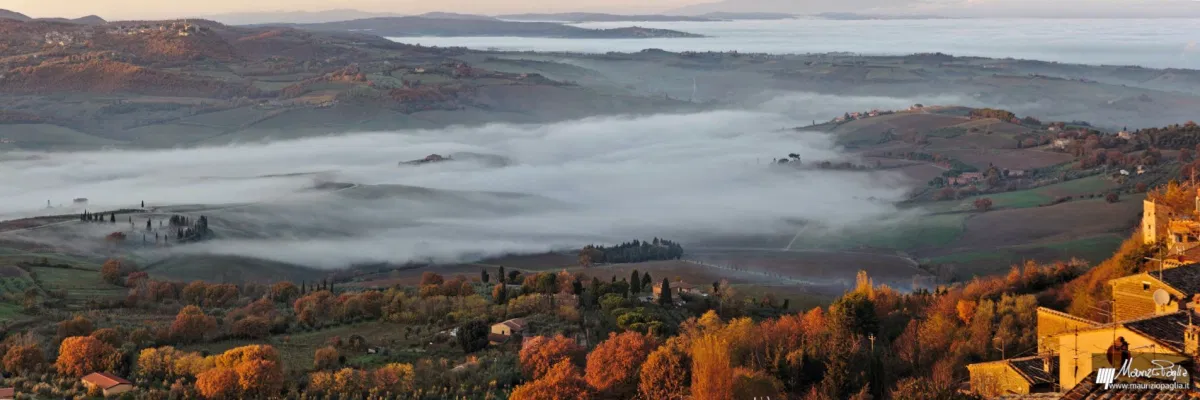 La vista mozzafiato che da Montepulciano si offre verso Pienza e la Val d'Orcia. I colori autunnali risaltano alla luce del tramonto e la nebbia, silenziosa, inizia a ricoprire la terra intrisa d'acqua.