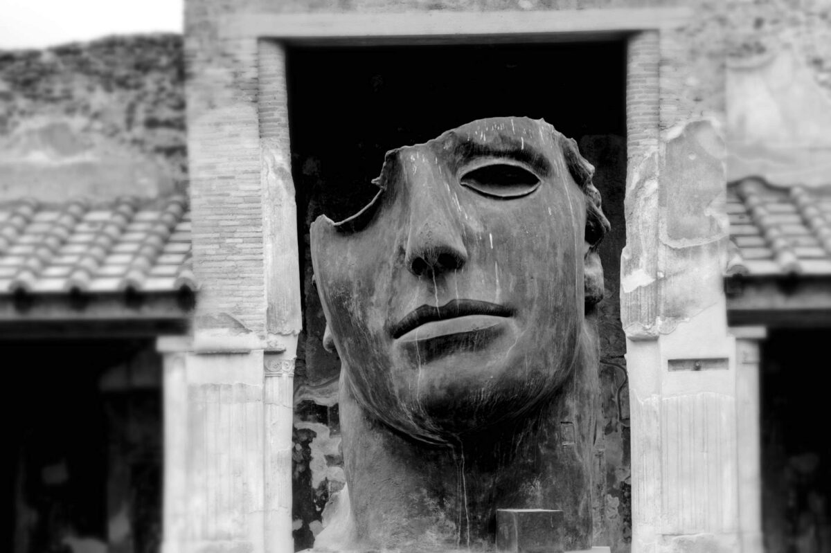 Maschera tragica tra le rovine di Pompei. La scultura è opera dell'artista Igor Mitoraj