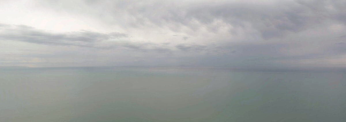 Un panorama del mare e del cielo che si confondono all'orizzonte in una cupa giornata di pioggia