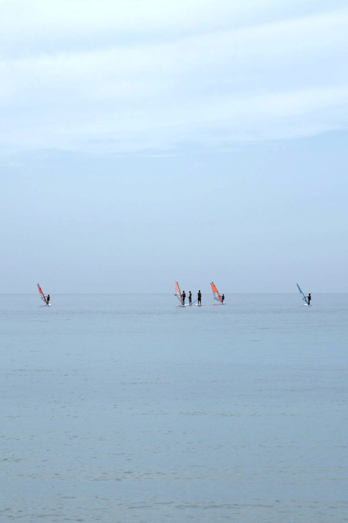 Un gruppo di surfisti scruta l'orizzonte di un mattino grigio e umido